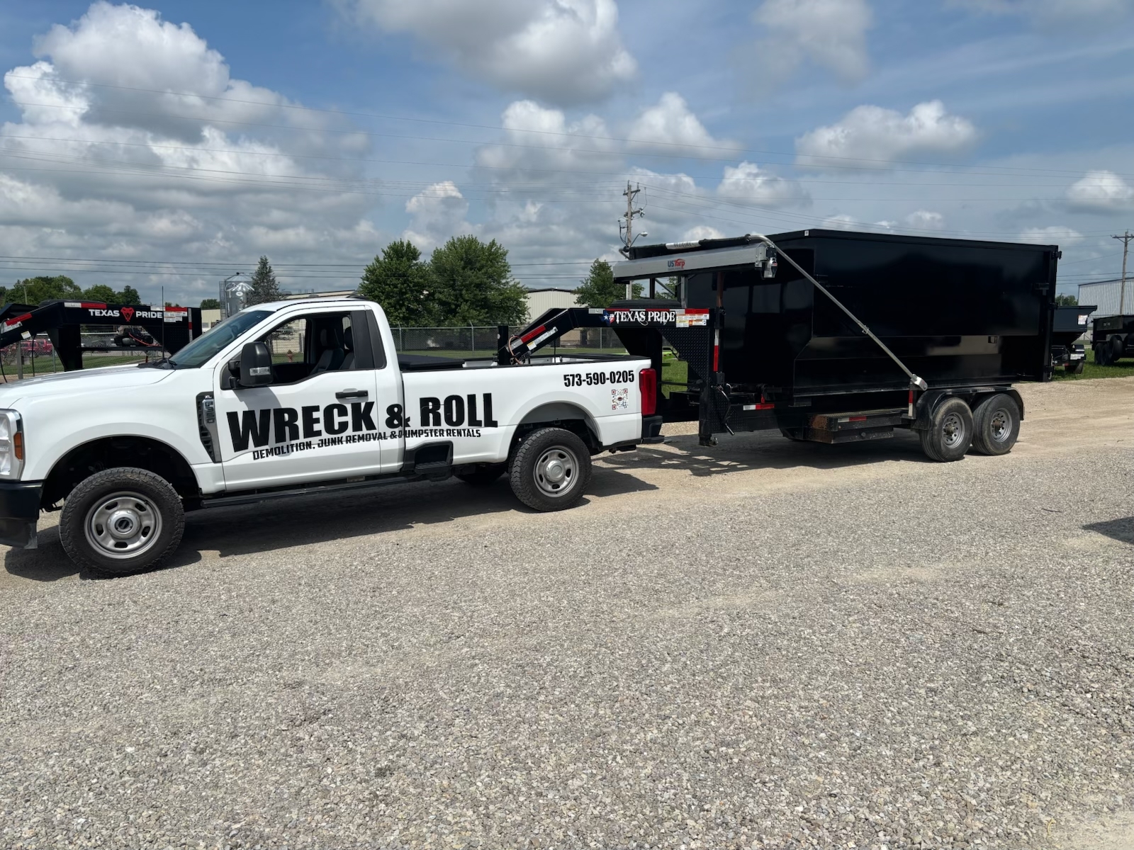 Wreck & Roll truck hauling a roll-off dumpster trailer